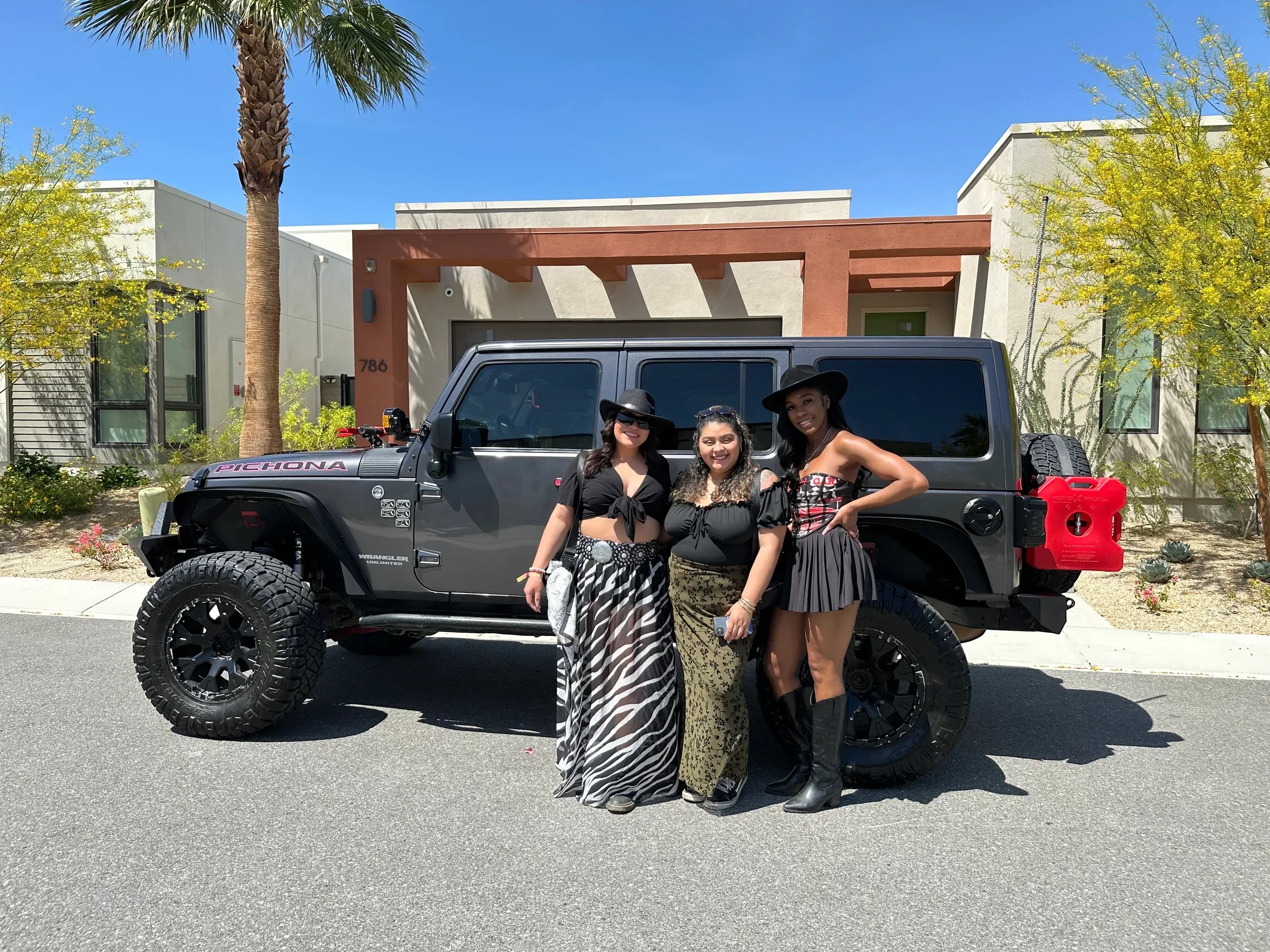 Three Coachella guests posing in front of a Jeep Wrangler